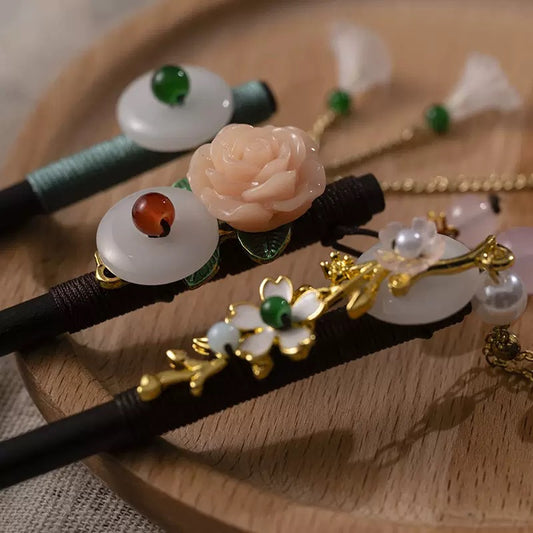 Decorative hair sticks with floral and gemstone designs on a wooden surface